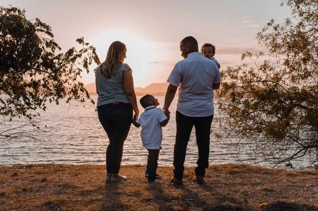 family standing outdoors by body of water