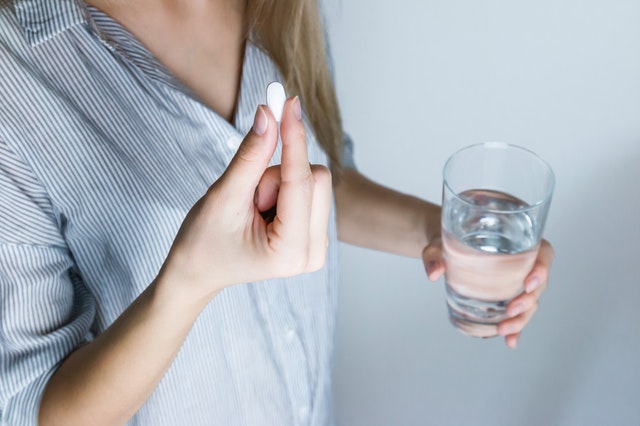 woman inside taking a pill