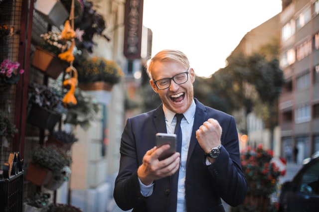 business man celebrating in street holding cellphone