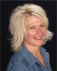 Julie Swim headshot wearing a blue top in front of a black background