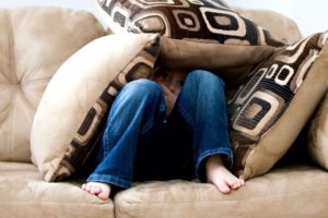 stock image of child hiding under couch cushions