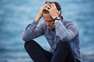 stock image of stressed man holding his head