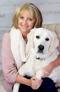 Susie Martinez sitting on a couch indoors with a therapy dog on her lap