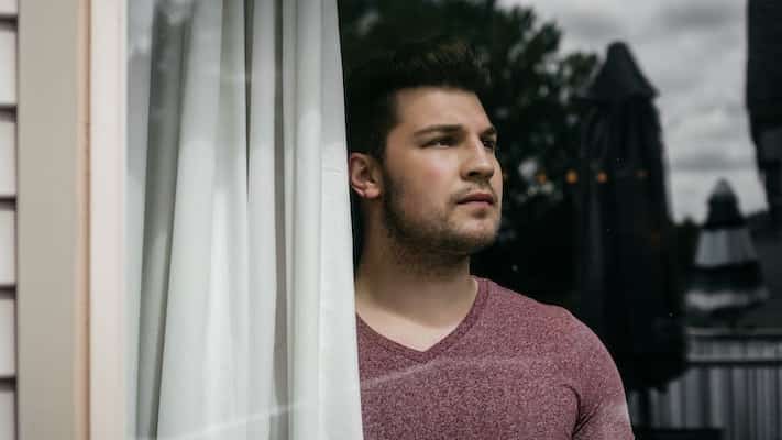 man looking outside through a window