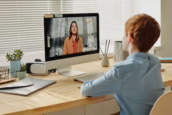 young boy sitting in front of computer receiving online therapy