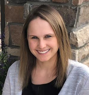 Therapist Brianna Roggow standing outdoors by a brick wall