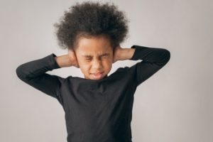 kid with black shirt covering ears