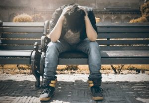 man sitting on bench with head down